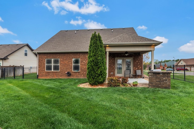 back of property with ceiling fan, a fenced backyard, a lawn, a patio area, and brick siding