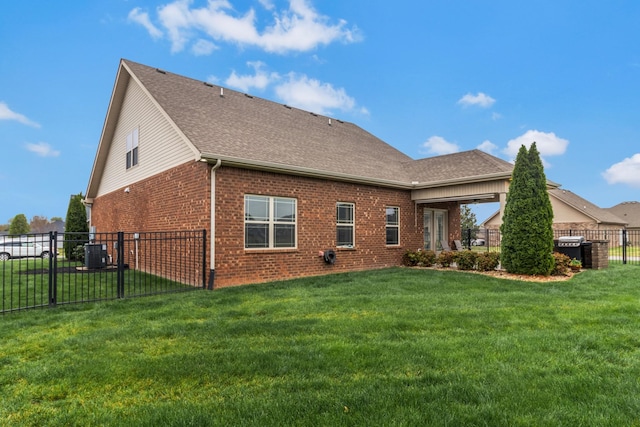 rear view of house featuring central AC, a lawn, roof with shingles, fence, and brick siding