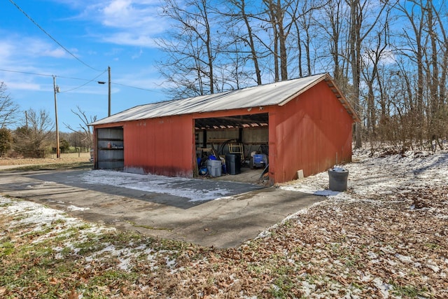 snow covered structure featuring an outdoor structure and an outbuilding