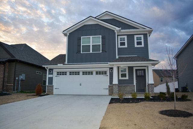 craftsman-style home featuring a garage, stone siding, driveway, and board and batten siding