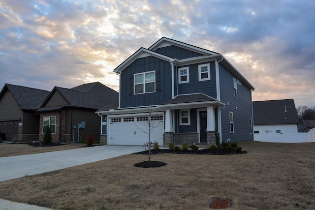 craftsman-style house featuring driveway, a garage, stone siding, board and batten siding, and a front yard