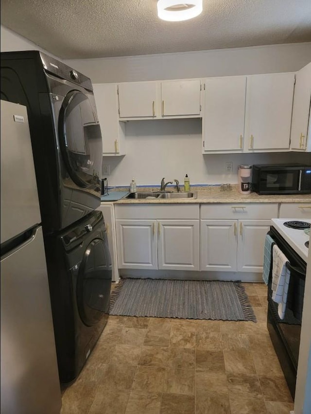 kitchen with stacked washer and dryer, white cabinetry, and black appliances