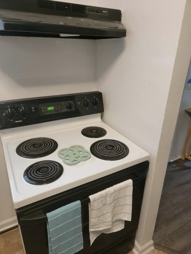 kitchen featuring under cabinet range hood, white cabinetry, light countertops, and range with electric stovetop