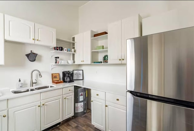 kitchen featuring dark wood-style flooring, freestanding refrigerator, light countertops, white cabinetry, and a sink