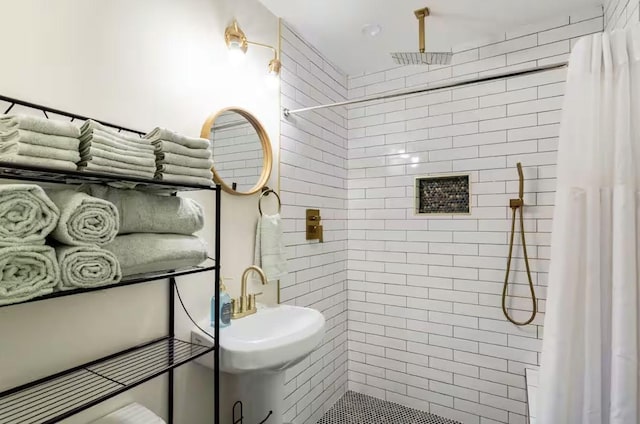 bathroom featuring tiled shower and a sink