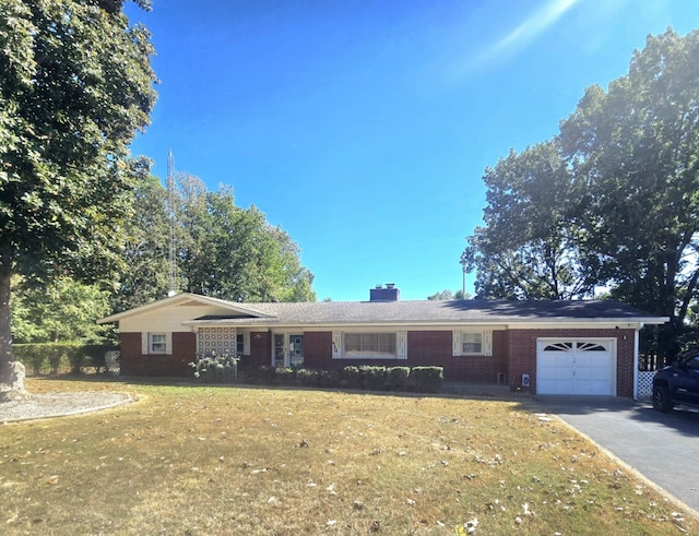 ranch-style house with a garage, brick siding, driveway, a front lawn, and a chimney