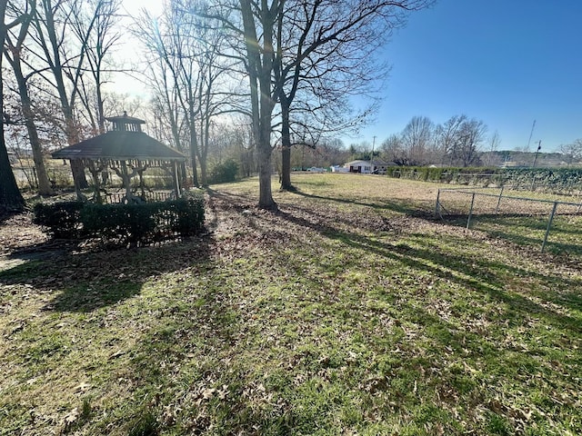 view of yard featuring a rural view, fence, and a gazebo