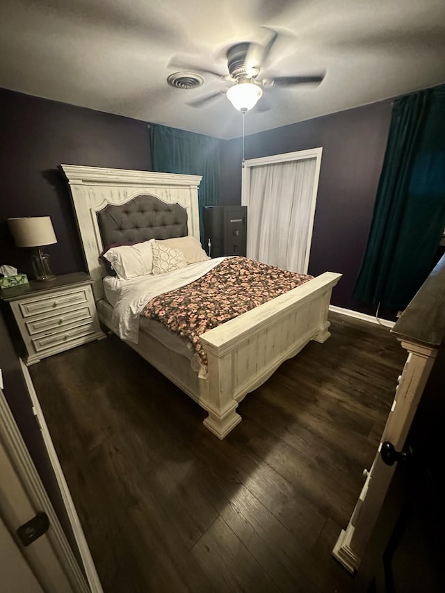 bedroom with dark wood-style floors, ceiling fan, visible vents, and baseboards