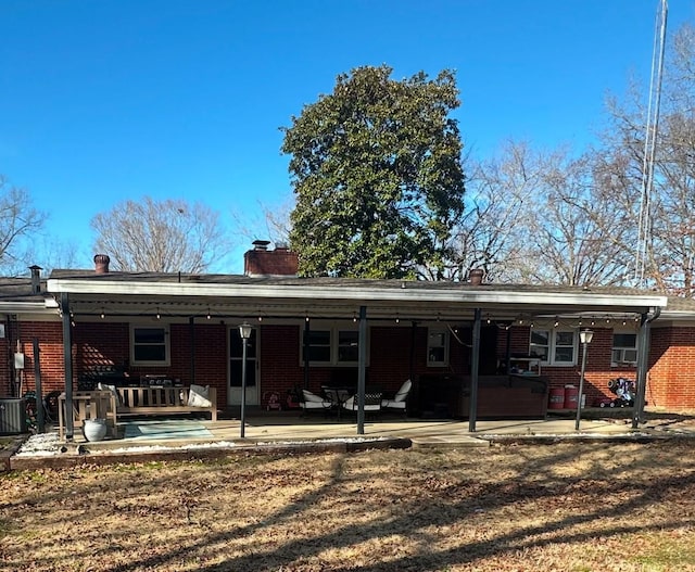 back of house featuring brick siding and a patio