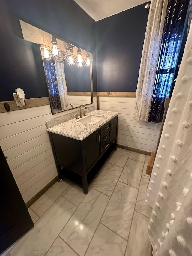 bathroom with marble finish floor, wainscoting, and vanity