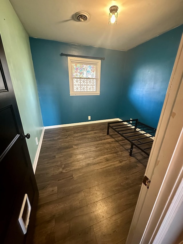 bedroom with wood finished floors, visible vents, and baseboards