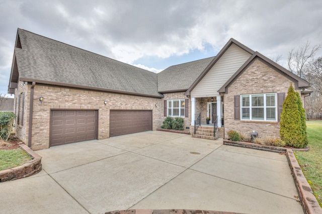 view of front of home featuring driveway, a shingled roof, a garage, and brick siding