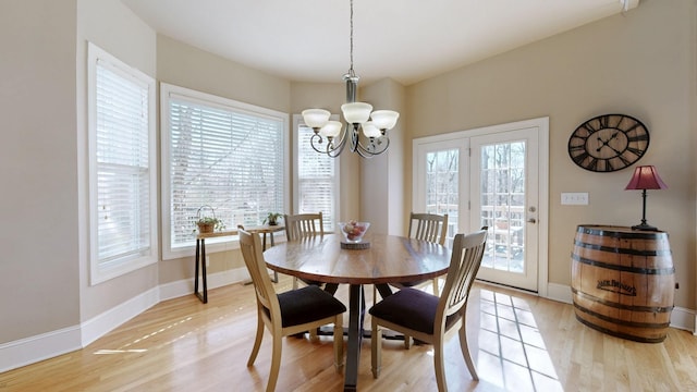 dining space featuring light wood-type flooring, baseboards, and a chandelier