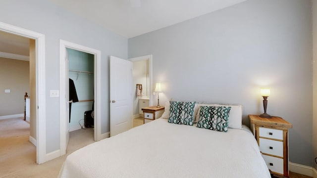 bedroom with a closet, light colored carpet, a spacious closet, and baseboards