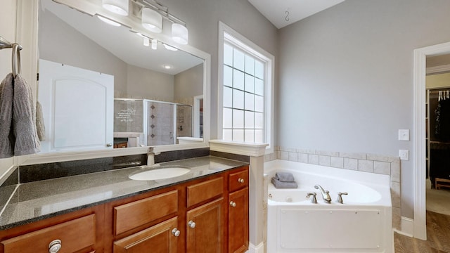 bathroom with a stall shower, a tub with jets, and vanity