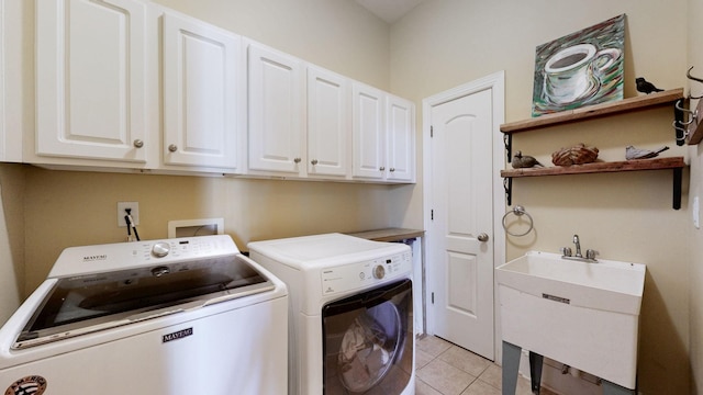 clothes washing area with light tile patterned floors, a sink, cabinet space, and washer and dryer