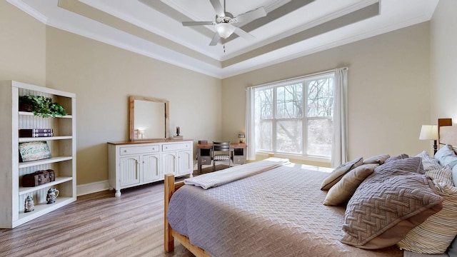 bedroom with light wood-style floors, ceiling fan, a tray ceiling, and ornamental molding