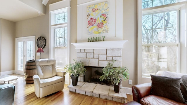 sitting room featuring a stone fireplace, wood finished floors, and baseboards