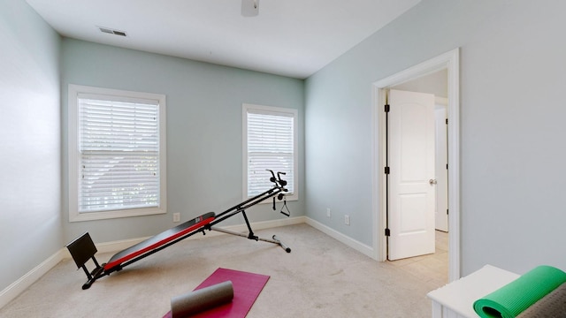 exercise room with baseboards, a healthy amount of sunlight, visible vents, and light colored carpet