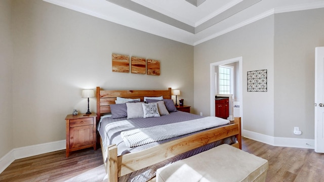 bedroom featuring ornamental molding, ensuite bathroom, baseboards, and wood finished floors