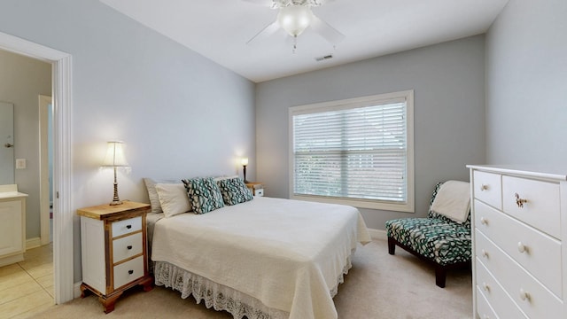 bedroom with ensuite bathroom, ceiling fan, light tile patterned flooring, light colored carpet, and visible vents