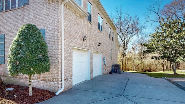 view of side of home featuring a garage, brick siding, and driveway