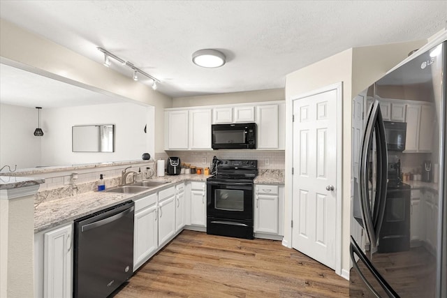 kitchen with light wood finished floors, white cabinets, a sink, black appliances, and backsplash