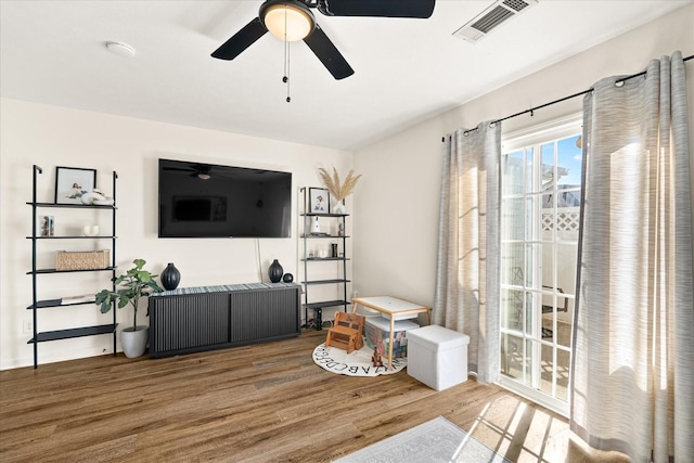 living room featuring ceiling fan, visible vents, and wood finished floors