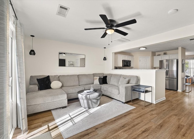 living area with ceiling fan, light wood-type flooring, and visible vents