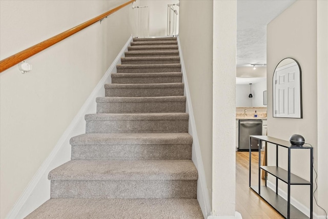 staircase featuring baseboards and wood finished floors