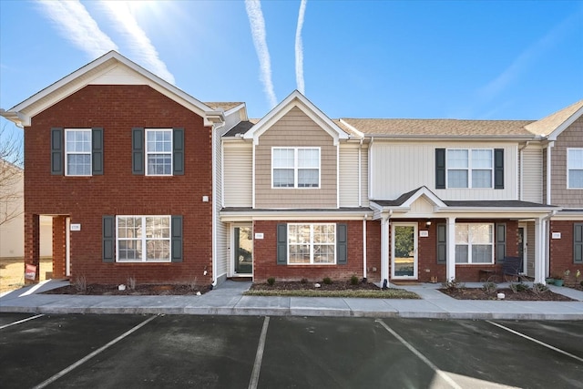 townhome / multi-family property featuring uncovered parking and brick siding