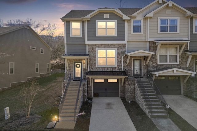 view of front of property featuring metal roof, a garage, stairs, concrete driveway, and a standing seam roof