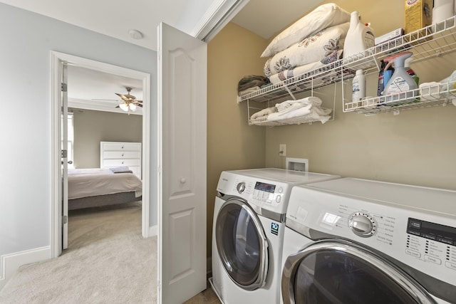 clothes washing area with washer and clothes dryer, light colored carpet, ceiling fan, laundry area, and baseboards