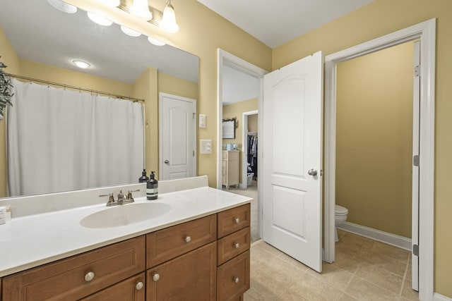 bathroom with tile patterned flooring, baseboards, vanity, and toilet