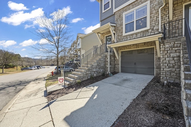 view of exterior entry with a garage, stone siding, and concrete driveway