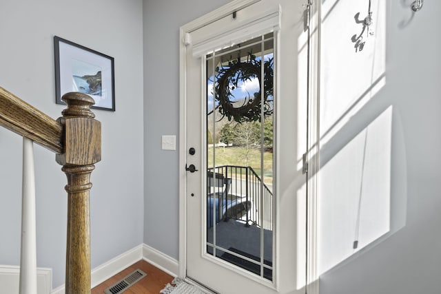 doorway with baseboards, visible vents, and wood finished floors