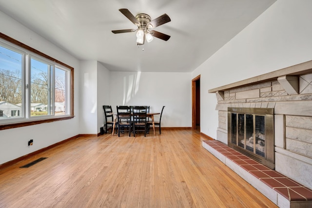 dining area featuring baseboards, visible vents, a tile fireplace, ceiling fan, and wood finished floors