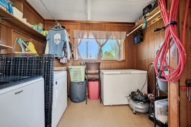 clothes washing area featuring laundry area, wooden walls, and washer and dryer