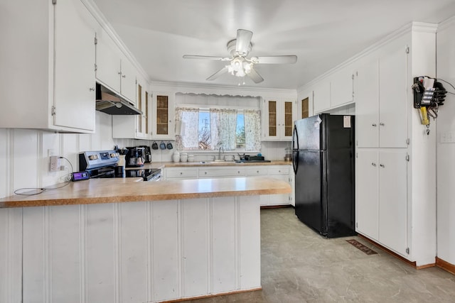 kitchen with electric stove, freestanding refrigerator, a sink, a peninsula, and under cabinet range hood