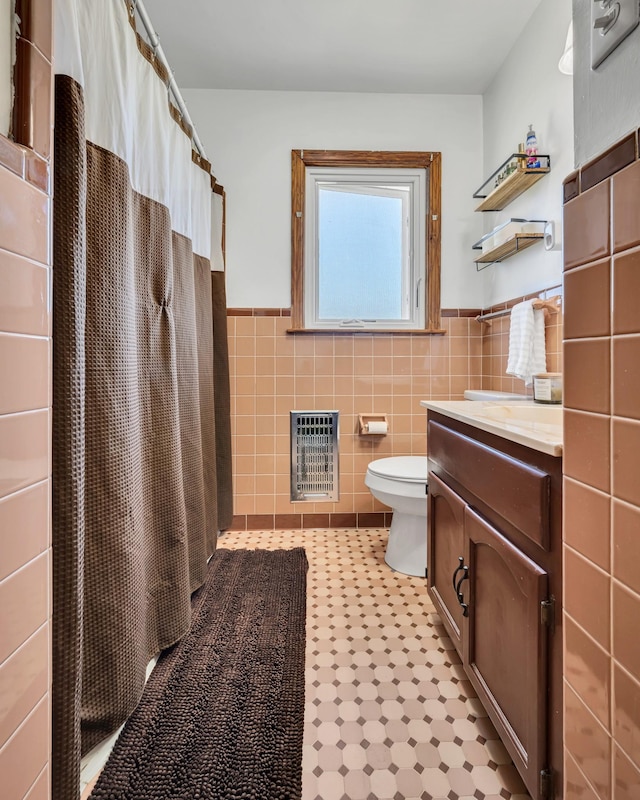 full bathroom with toilet, vanity, tile walls, wainscoting, and heating unit