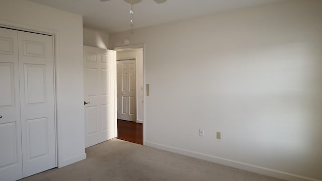 unfurnished bedroom with carpet floors, a ceiling fan, baseboards, and a closet