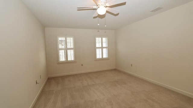 unfurnished room featuring a ceiling fan, light colored carpet, visible vents, and baseboards