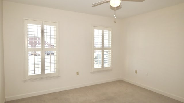 empty room featuring light carpet, ceiling fan, and baseboards