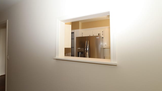 interior details featuring white cabinets, light countertops, and stainless steel fridge with ice dispenser