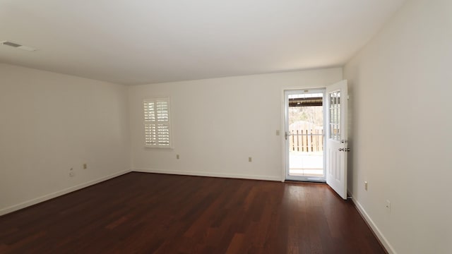 spare room featuring visible vents, dark wood finished floors, and baseboards