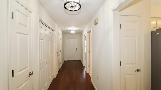 corridor with dark wood-type flooring and baseboards