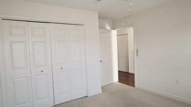 unfurnished bedroom with a closet, light carpet, and baseboards