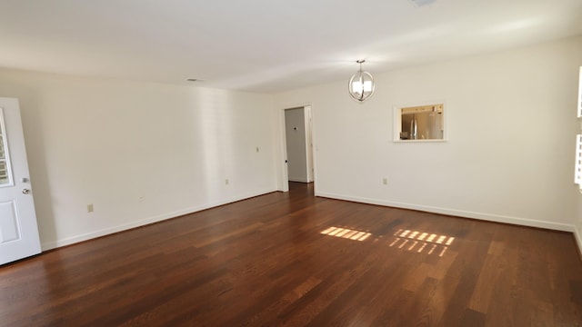 empty room with dark wood-style flooring, visible vents, and baseboards