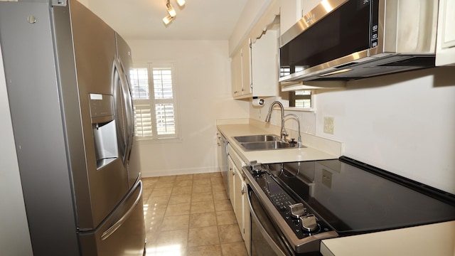 kitchen with white cabinetry, stainless steel appliances, a sink, and light countertops