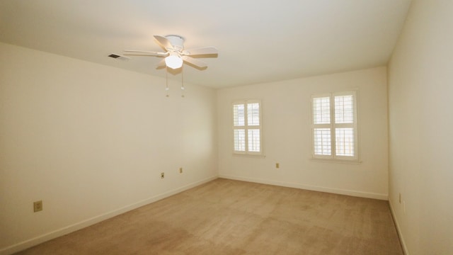 empty room featuring baseboards, ceiling fan, visible vents, and light colored carpet